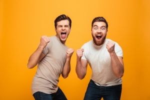 Two guys cheering on a solid colored background
